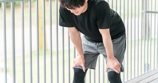 走って疲れた男性。膝に手をおいて何とか立っている様子。