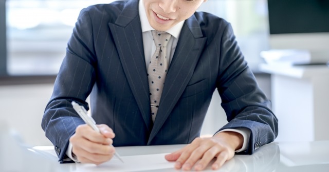 就活中の若者。リクルートスーツで履歴書を作成している様子。