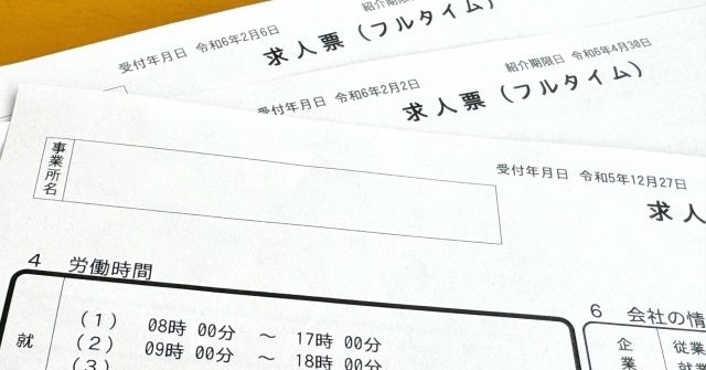 机の上に複数の求人票が重ねて置いてある様子。