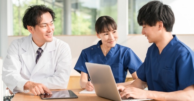 白衣姿の男女3人、医療スタッフ同士でコミュニケーションを取っている様子。