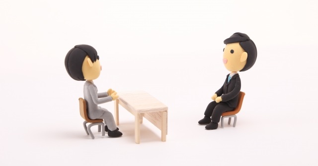 面接の様子を表す２対の人形。対面で座っている。