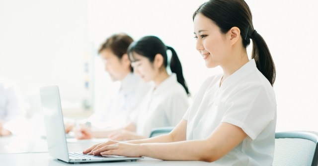 白衣姿の男女３人。パソコンでカルテを記載している様子。