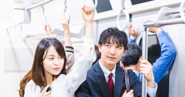 通勤電車の様子。吊革につかまり踏ん張っている様子。