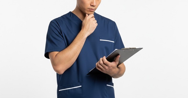 バインダーを持ち考え込む医療従事者。