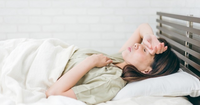 ぐったりしてベッドに寝ている女性。