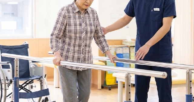 平行棒で歩くリハビリをしている女性。近くで介助をする男性理学療法士。