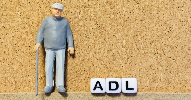 杖を使って立っている高齢者のフィギュア。ADLの文字あり。