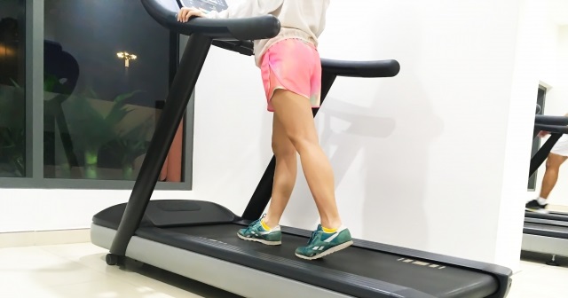 トレッドミルで歩行する女性。